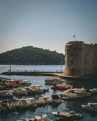 Sailboats moored on sea by buildings against clear sky