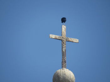 Low angle view of cross against clear blue sky