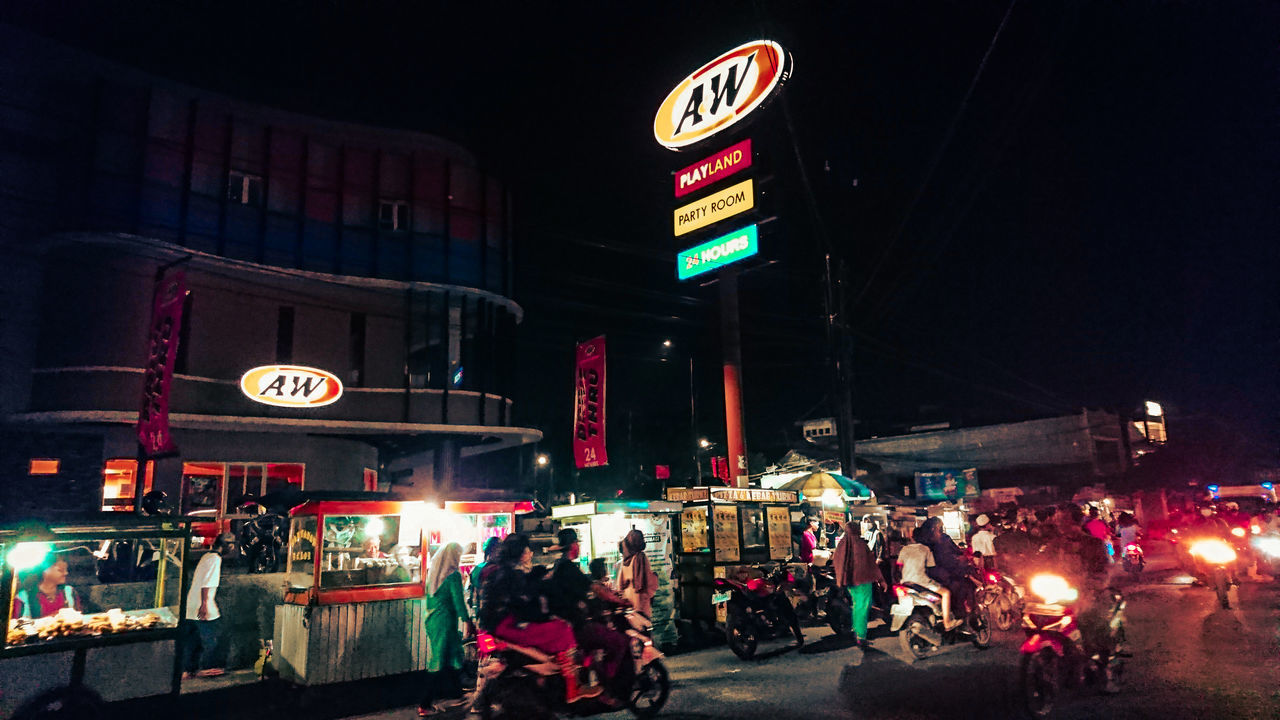 PEOPLE ON ILLUMINATED STREET AT NIGHT