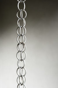Close-up of chains hanging against gray background