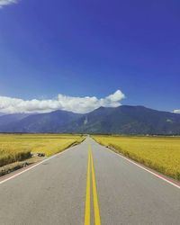 Road amidst landscape against blue sky