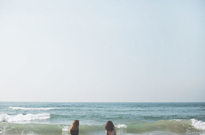 Girls at beach against clear sky