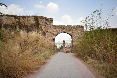 Archway of old ruin building against sky