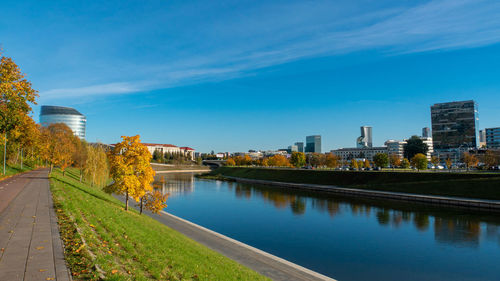 River by buildings against blue sky