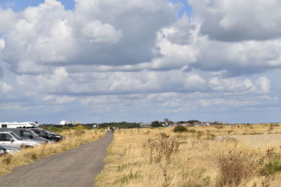 Road amidst field against sky