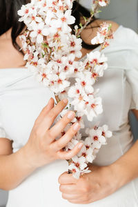 Midsection of woman holding white flowering plant