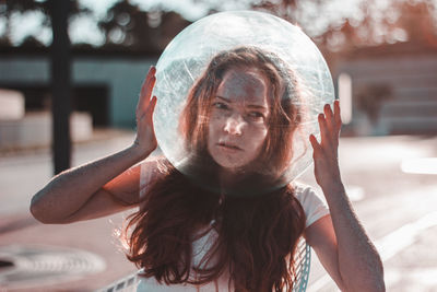 Close-up of young woman wearing glass container outdoors