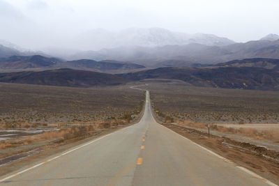 Road leading towards mountains against sky