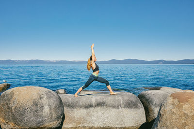 Young woman practicing yoga on lake tahoe in northern california.