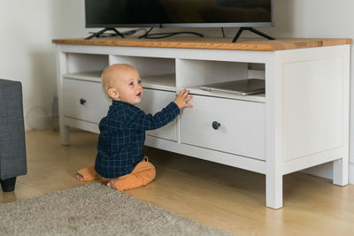 Side view of boy sitting on bed at home