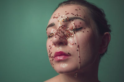 Close-up of woman with water and star shape decoration against green background