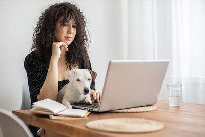 Portrait of woman using mobile phone while sitting on table