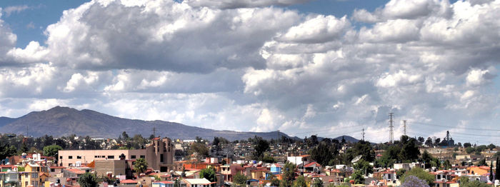 Panoramic view of town by mountains against sky