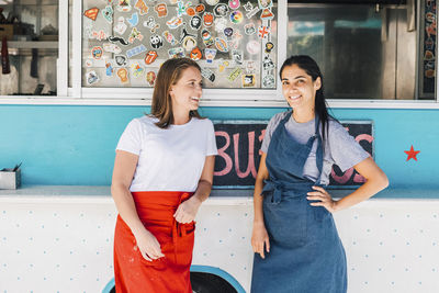 Confident young multi-ethnic female owners standing against food truck