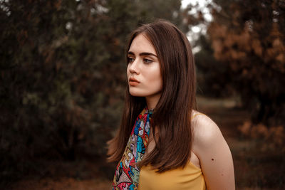 Portrait of beautiful woman standing against tree