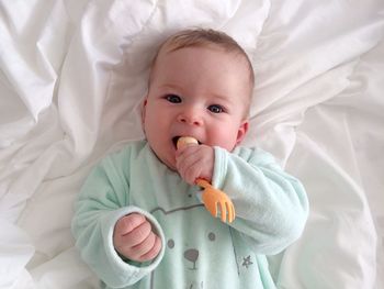 High angle portrait of cute baby girl lying on bed at home