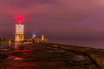 Lighthouse by sea against sky at night