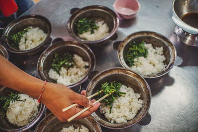 Cropped image of hand holding food in chopsticks