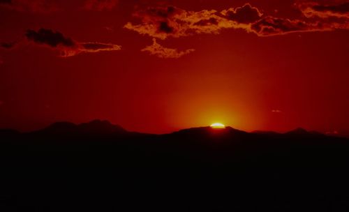 Scenic view of silhouette mountains against romantic sky at sunset