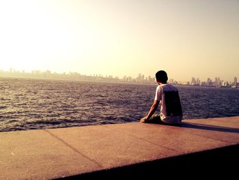 Rear view of man looking at sea against clear sky