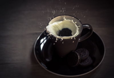 High angle view of milk splashing in coffee cup on table