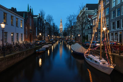 Boats moored in canal amidst buildings leading towards westerkerk