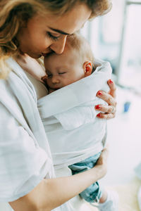 Mother carrying newborn son at home