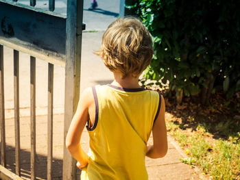 Rear view of boy standing by gate