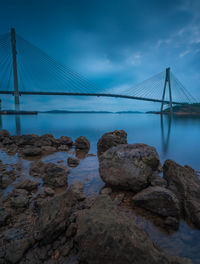 Suspension bridge over sea against sky