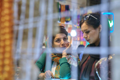 Portrait of young woman looking through window at store