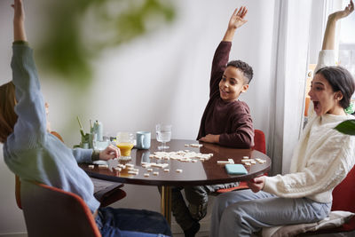 Girl and boys playing scrabble at dining table