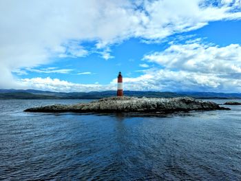 Lighthouse by sea against sky