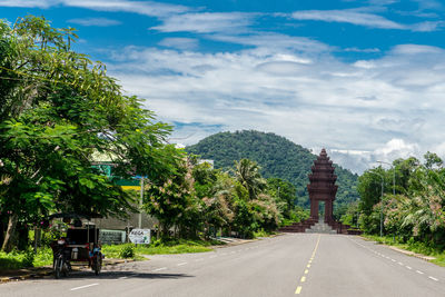 Rear view of road by trees against sky