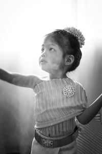 Girl looking away while standing against wall