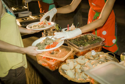 Midsection of waitress serving food to woman at ceremony