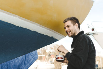 Smiling man painting boat