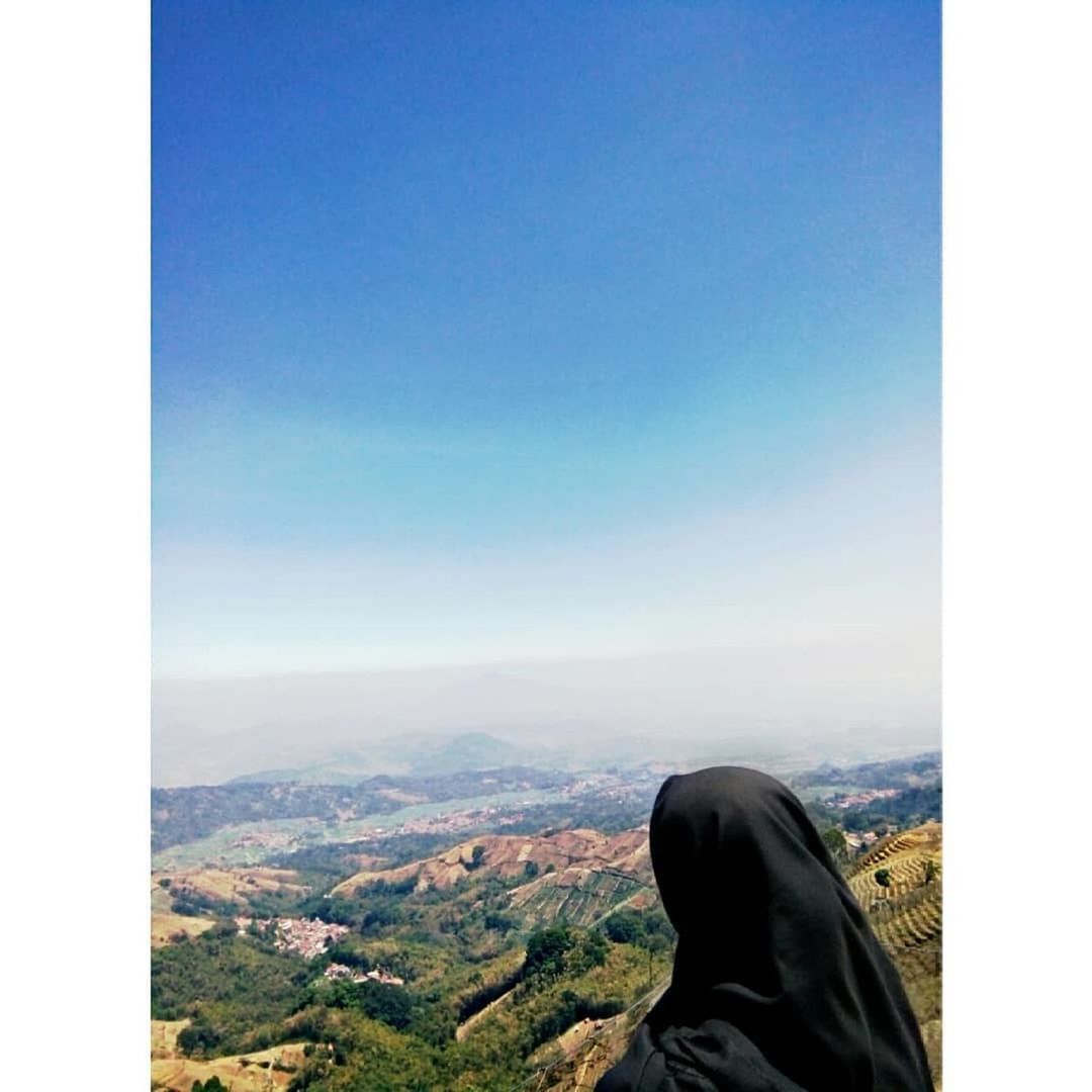 sky, one person, nature, human leg, scenics - nature, low section, day, personal perspective, blue, copy space, shoe, clear sky, leisure activity, landscape, lifestyles, mountain, outdoors, beauty in nature, environment, architecture, limb, cityscape, footwear, horizon, human limb, tranquil scene, city, adult, tranquility, travel, travel destinations, human foot, sunlight, building exterior, standing, built structure, horizon over land, looking at view, high angle view, relaxation