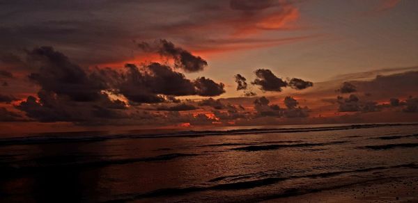 Scenic view of sea against dramatic sky during sunset