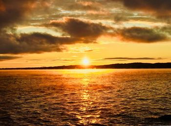 Scenic view of sea against dramatic sky during sunset