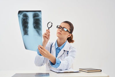 Doctor examining x-ray against white background