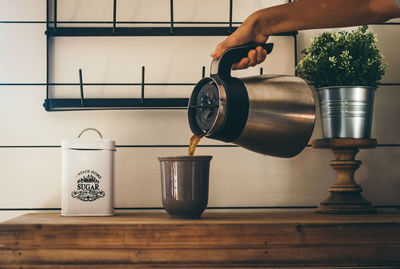 Cropped hand pouring black tea in container