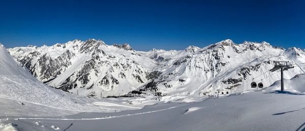 Scenic view of snowcapped mountains against clear blue sky