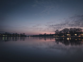 Reflection of trees in lake at sunset