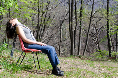 Woman sitting on tree trunk in forest