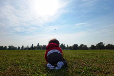 Rear view of woman sitting on field