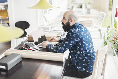 Side view of male architect sitting at table in home office