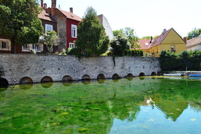 Houses by river against sky