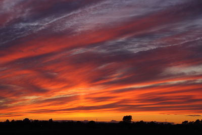 Scenic view of dramatic sky over silhouette landscape