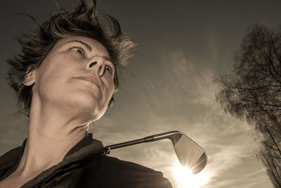 Low angle view of young man looking away against sky