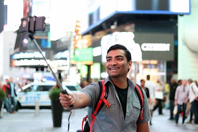 Smiling man taking selfie in city